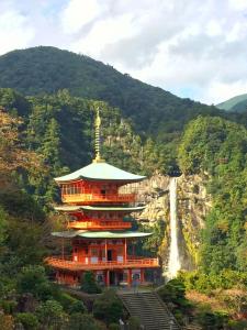 un grand bâtiment avec une cascade en arrière-plan dans l'établissement Tsukiji Hostel Wakayama 3, à Wakayama