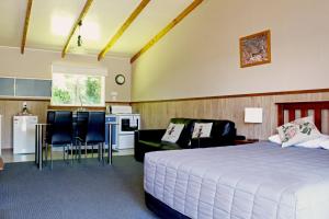 a bedroom with a white bed and a kitchen and a kitchen at Fairy Springs Motel in Rotorua