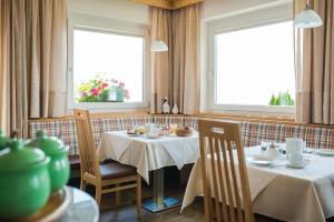 a dining room with two tables and two windows at Garni Georgenhöhe in Schenna