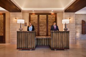 a man and a woman standing at a counter in a lobby at The Setai Tel Aviv in Tel Aviv