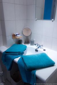 een badkamer met twee blauwe handdoeken op een wastafel bij Confluences in Walcourt