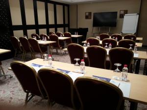 una sala de conferencias con mesas, sillas y una pantalla en Mena Hotel Al Jubail, en Al Jubail