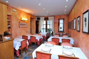a restaurant with white tables and red chairs at Hotel Fonda Merce in Llivia