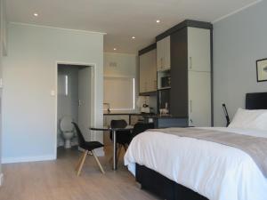 a bedroom with a bed and a desk and a kitchen at Oranjehof Studios in Cape Town