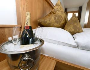 twee flessen wijn in een emmer naast een bed bij Hotel Alpina in Fiesch +22 foto's