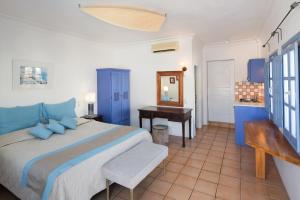 Schlafzimmer mit einem Bett, einem Schreibtisch und einem Spiegel in der Unterkunft Meltemi Suites in Perissa
