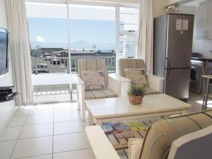 a living room with a refrigerator and a table and chairs at Point Village Accommodation - Alista in Mossel Bay