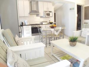 a kitchen and living room with white chairs and a table at Point Village Accommodation - Alista in Mossel Bay +8 photos