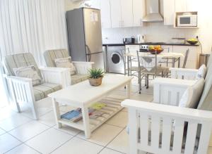 a kitchen and living room with white chairs and a table at Point Village Accommodation - Alista in Mossel Bay