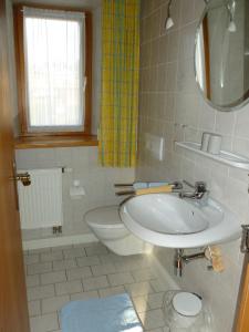 bagno con lavandino, servizi igienici e specchio di Ferienwohnung Maag a Lechbruck