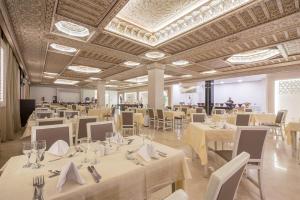 um salão de banquetes com mesas e cadeiras brancas em Pickalbatros Aqua Fun Club All inclusive em Marraquexe