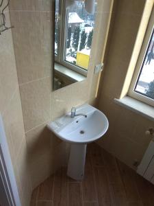 La salle de bains est pourvue d'un lavabo blanc et d'un miroir. dans l'établissement Inn Sport, à Tchernivtsi