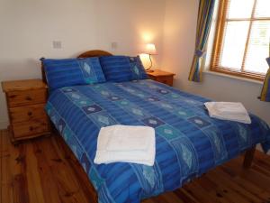 a bedroom with a blue bed with two towels on it at Achill Sound Holiday Village in Achill Sound