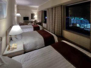 a hotel room with two beds and a flat screen tv at Miyako Hotel Yokkaichi in Yokkaichi