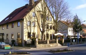 un grand bâtiment blanc avec un toit marron dans l'établissement Gasthof Gruner Baum, à Bayreuth