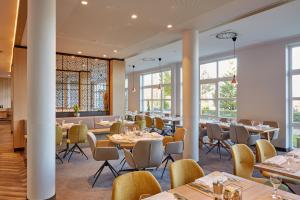 a dining room with tables and chairs and windows at H+ Hotel Limes Thermen Aalen in Aalen