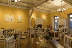 a dining room with tables and white chairs at Landhaus Ribbeck in Ribbeck