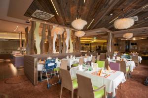ein Restaurant mit weißen Tischen, Stühlen und Kronleuchtern in der Unterkunft Allegria Resort Stegersbach - Allegria Hotel in Stegersbach