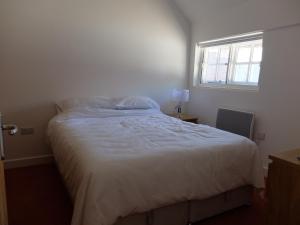ein weißes Bett in einem Schlafzimmer mit einem Fenster in der Unterkunft The Thatched Barn in Thame