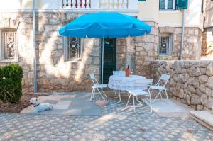 una mesa y sillas bajo una sombrilla azul en Apartments Carmen & Tosca, en Dubrovnik