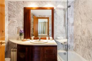 a bathroom with a sink and a tub and a mirror at 1410 - Mediterranean Forum Apartment in Barcelona