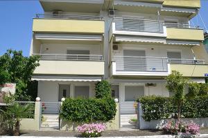 a white building with bushes and flowers in front of it at Luxury Equiped Apartment - Olympic Beach in Olympic Beach