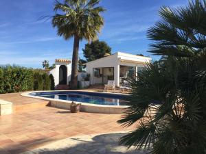a house with a swimming pool and a palm tree at Apartamento Villa Joya in Benissa