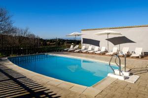 una piscina con sillas y sombrillas en Can Barnosell - Els Masos d'en Coll, en Llaviá