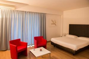 um quarto de hotel com uma cama e duas cadeiras vermelhas em Park Hotel Residence em Crema