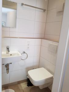 Baño blanco con aseo y lavamanos en Hotel Pension Haus Pooth, en Wesel