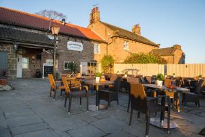 un patio con mesas y sillas frente a un edificio en The Kestrel by Innkeeper's Collection, en Harrogate