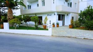 une maison blanche avec une clôture et une allée. dans l'établissement Mastorakis Hotel and Studios, à Chersónissos