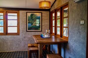 a dining room with a wooden table and windows at Cozycomo Chiang Dao - Wiang Mek in Chiang Dao