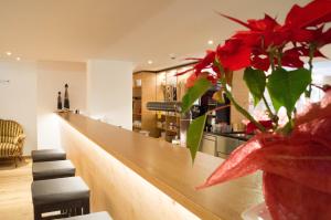 un bar con un jarrón con flores rojas delante en Hotel Gasthof Adler, en Lingenau