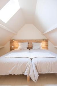 a bedroom with a white bed with a wooden headboard at Le Pave de la Croix Blanche in Le Pavé