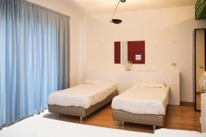 two beds in a room with blue curtains at Park Hotel Residence in Crema