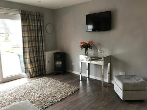 a living room with a table and a tv on the wall at Carriage Cottage Hot Tub in Beith