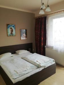 a bedroom with a bed with white sheets and a window at Penzión Rekrea in Levice