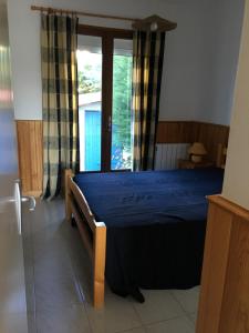 een slaapkamer met een blauw bed en een raam bij Residence la Catalane in Saint Cyprien Plage