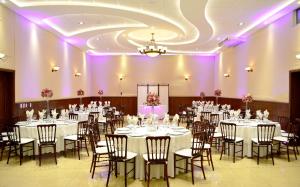 a banquet hall with white tables and chairs and purple lighting at Arcángel Puebla in Puebla