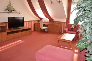 a living room with a tv and a chair and a table at Penzion na Potočnej in Skalica