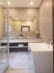 a bathroom with a tub and a large mirror at Suikerbossie Guesthouse in Bloemfontein