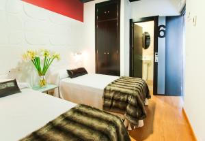 una habitación de hotel con 2 camas y un jarrón de flores en Narayana Casa Camilo, en El Cerro de Andévalo