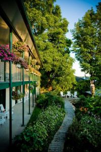 a walkway next to a building with white chairs and flowers at The Gananoque Inn & Spa in Gananoque