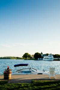 ein Boot an einem Dock mit zwei Booten im Wasser angedockt in der Unterkunft The Gananoque Inn & Spa in Gananoque