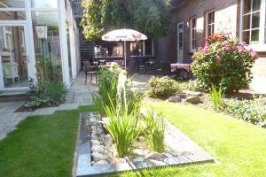 um jardim com um pátio com um guarda-sol e relva em Hotel Pension Haus Pooth em Wesel
