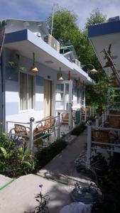 a white house with wooden chairs and a porch at Nostress Guest House in Mui Ne