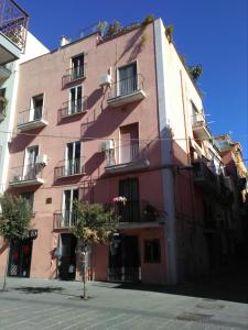 a pink building with balconies and a tree in front of it at Il Nido della Quaglia in Pozzuoli