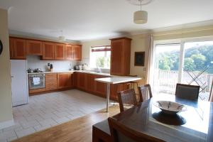 uma cozinha com armários de madeira, uma mesa e uma sala de jantar em Glen Ard Holiday Home No 1 em Dunmore East