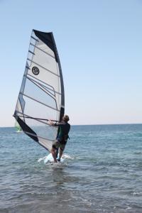 a man is standing in the water with a sail at Flow Datca Surf & Beach Hotel in Datca